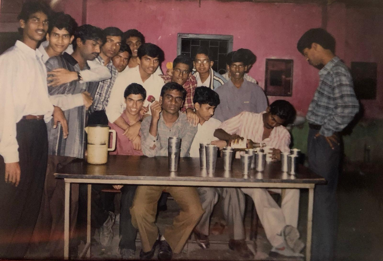 Friends gathered around the hostel mess table with steel tumblers